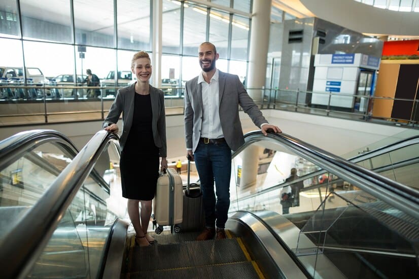 souriant gens d’affaires avec bagages monter l’escalator